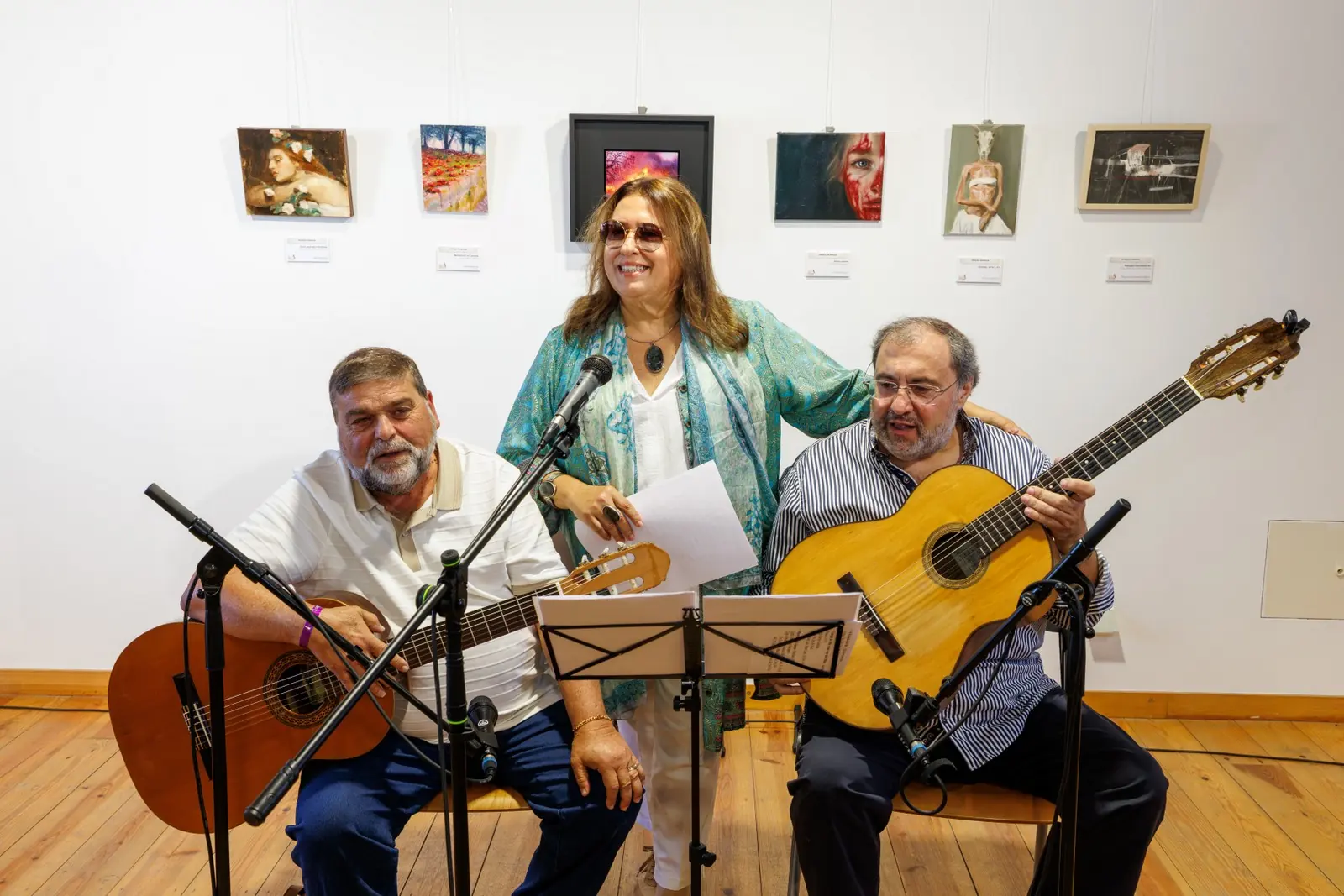 Dois guitarristas e uma cantora a actuar diante das obras expostas